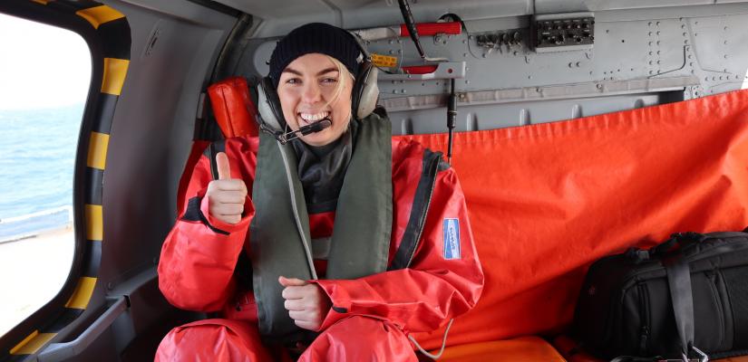 Image of a female AFMA Fisheries Officer strapped into a seat in a helicopter as part of the joint Australia-France patrol of the Southern Ocean.